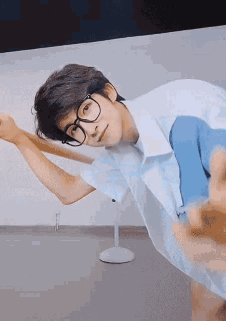 a young man wearing glasses and a blue shirt is laying on his back .