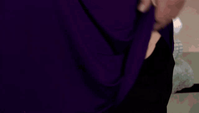 a woman in a purple shirt is holding her belly with her hands