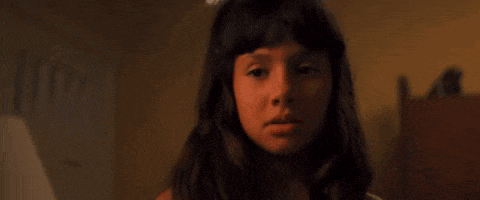 a young girl with long hair is making a funny face in a dark room .