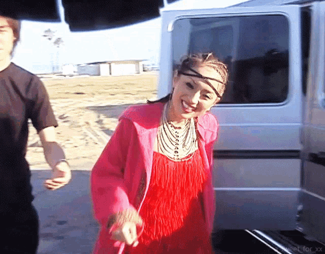 a woman in a red dress is standing next to a white van