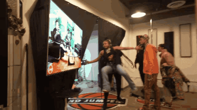 a group of people are dancing in front of a large screen that says no jump