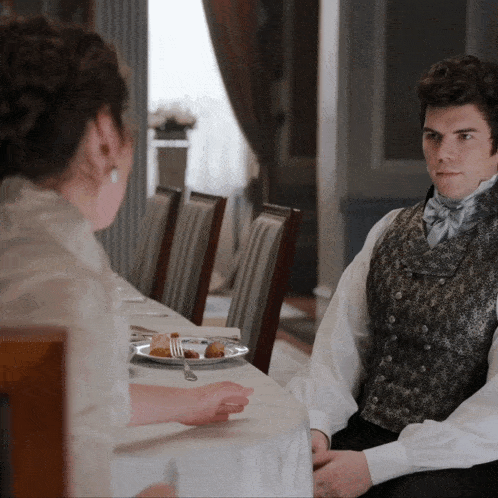 a man and a woman are sitting at a table with plates of food