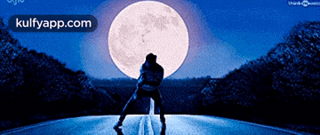 a picture of a man standing in front of a full moon with kulfyapp.com on the bottom right