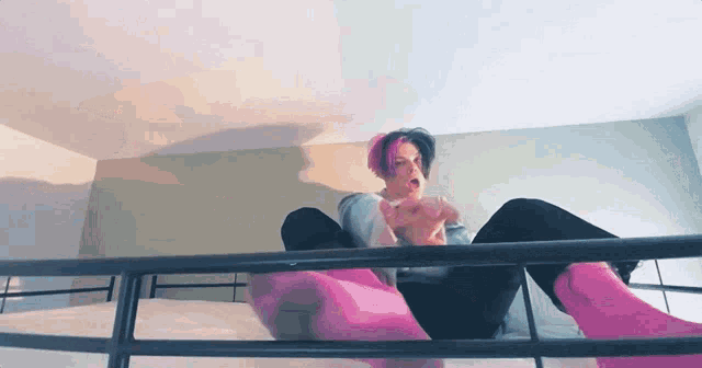 a person with pink hair and pink socks is sitting on a bed