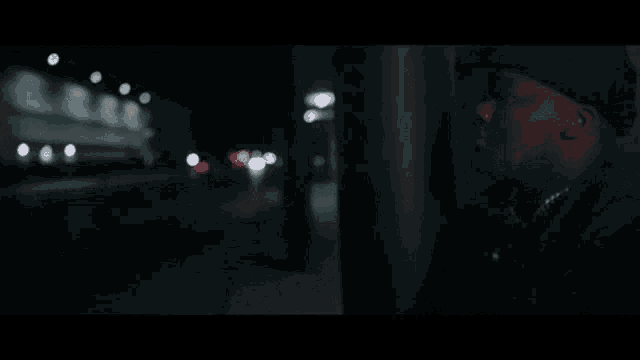 a man in a black jacket and hat stands in the dark