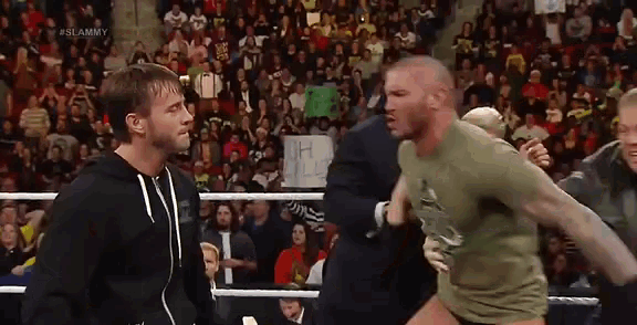 two wrestlers are standing in a wrestling ring talking to each other .