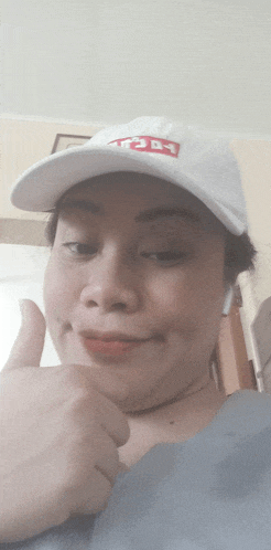 a woman wearing a white hat with the word today on it is giving a thumbs up