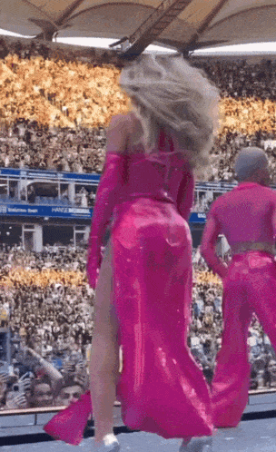 a woman in a pink dress is dancing on stage in front of a crowd