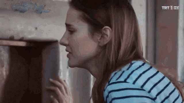 a woman in a striped shirt is looking at something in a room .