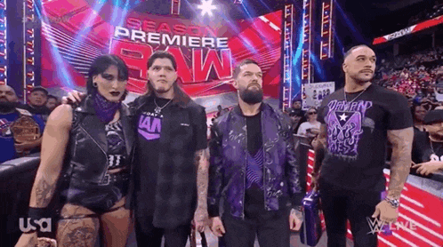 a group of wrestlers are standing next to each other on a stage in front of a crowd .