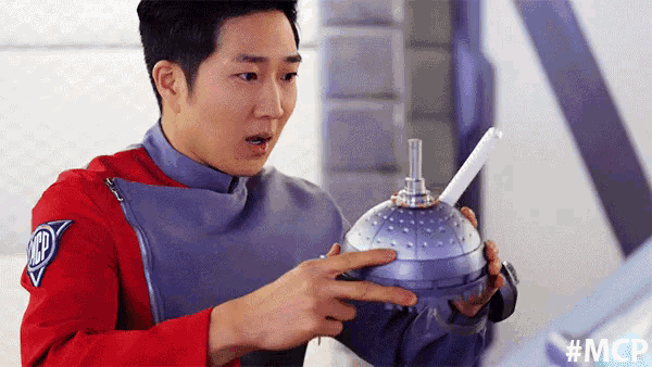 a man in a red jacket is pointing at a purple object