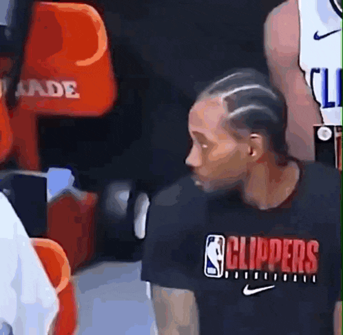 a man wearing a black shirt that says clippers is standing in a locker room
