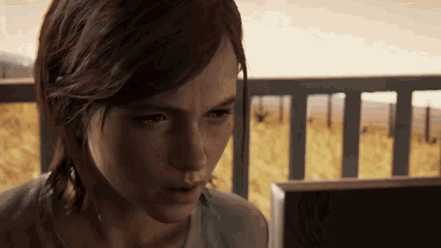 a woman is sitting on a balcony looking at a laptop screen .