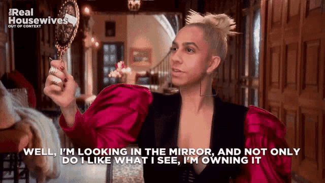 a woman in a red dress is holding a mirror and says well i 'm looking in the mirror