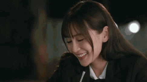 a woman in a black jacket and white shirt smiles