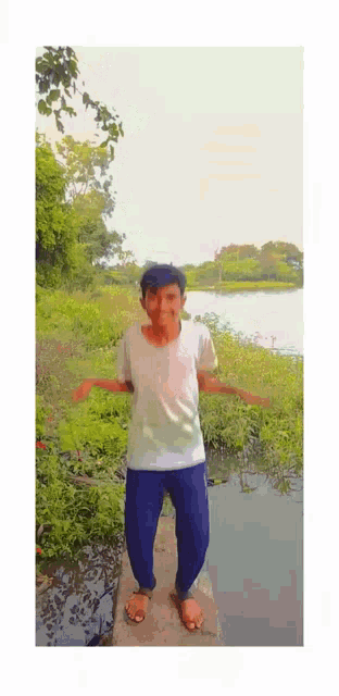 a man in a white shirt and blue pants is standing on a bridge over a body of water .