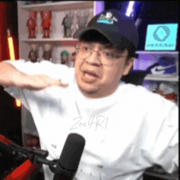 a man wearing a baseball cap and glasses is standing in front of a microphone .