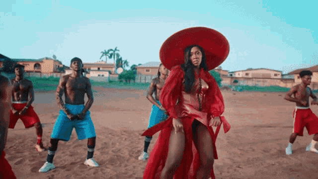 a woman in a red dress is dancing with a group of men in red shorts
