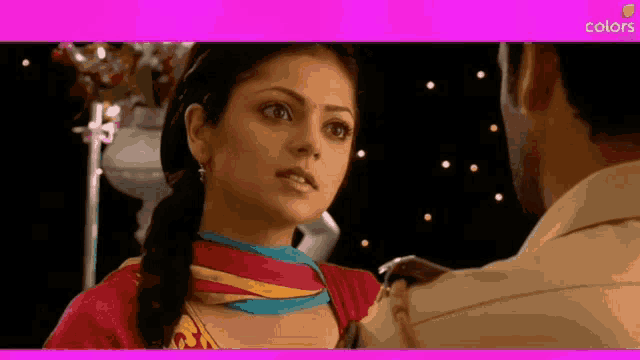 a woman in a red dress is looking at a man in a tan shirt with a pink background that says colors on it