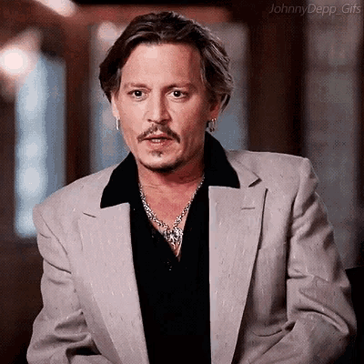 johnny depp is wearing a suit and a black shirt and a necklace .