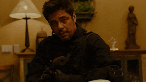 a man in a black jacket holds a gun