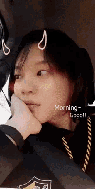a woman sitting in a car with her hand on her face and the words morning gogo written below her