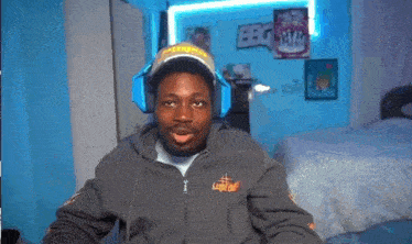 a man wearing headphones and a hat with the word ebg on it looks at the camera
