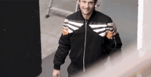 a man wearing a black jacket with white stripes on the sleeves is walking down stairs .