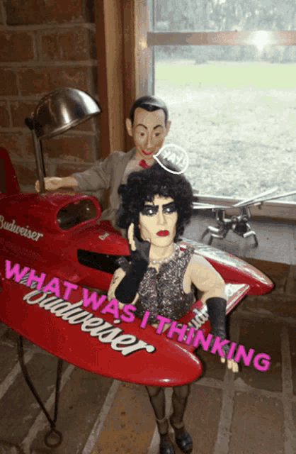 a budweiser boat sits on a table next to two dolls