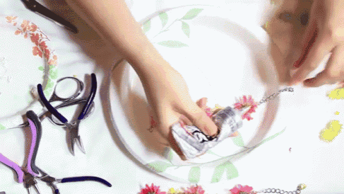 a person is making a necklace with flowers and a paper plate