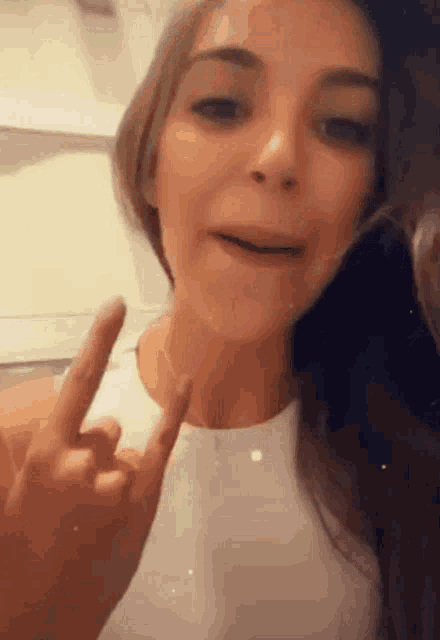 a woman is making a peace sign with her fingers .