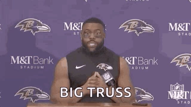 a man stands at a podium with the words big truss written on the screen behind him