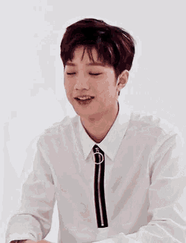 a young man wearing a white shirt and tie is smiling .