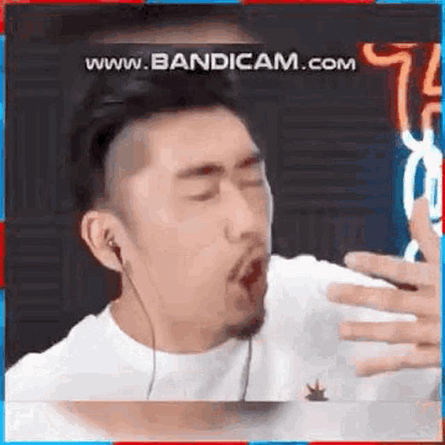 a man with a beard is wearing headphones and making a funny face while singing into a microphone .