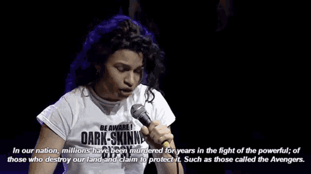 a woman is speaking into a microphone while wearing a shirt that says be aware dark skinned gypsy