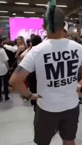a man with a mohawk wears a white shirt that says fuck me jesus