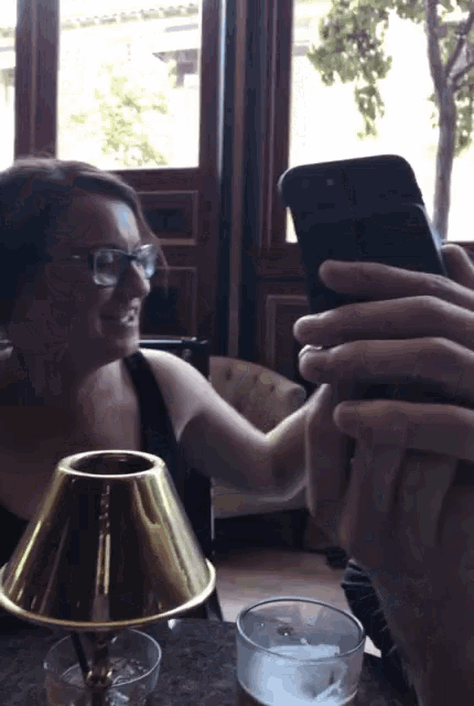 a woman wearing glasses is taking a picture of herself with her phone
