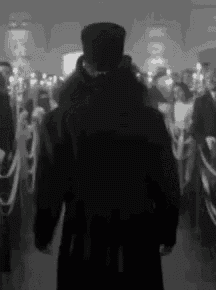 a black and white photo of a man in a top hat standing in a crowd of people .