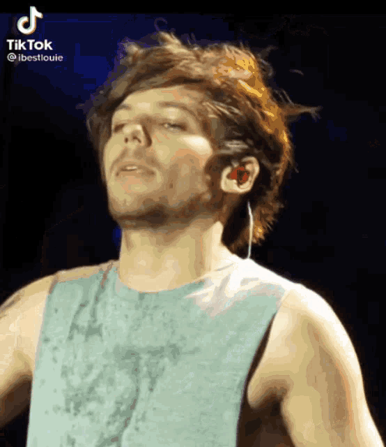 a man wearing a blue tank top and red ear buds has tiktok written on the bottom right