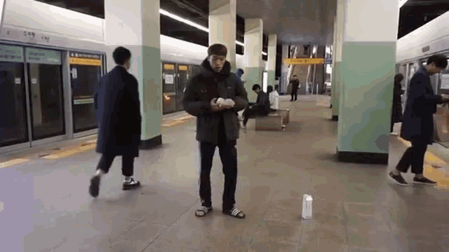 a man standing in a subway station with a yellow sign that says ' a ' on it