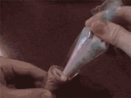 a person is piping frosting into a plastic bag on a cupcake .