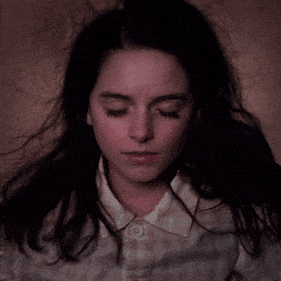 a close up of a young girl 's face with a button on her shirt