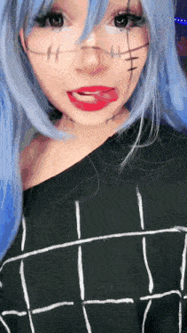a woman with blue hair is wearing a black shirt with white lines on it and making a funny face .