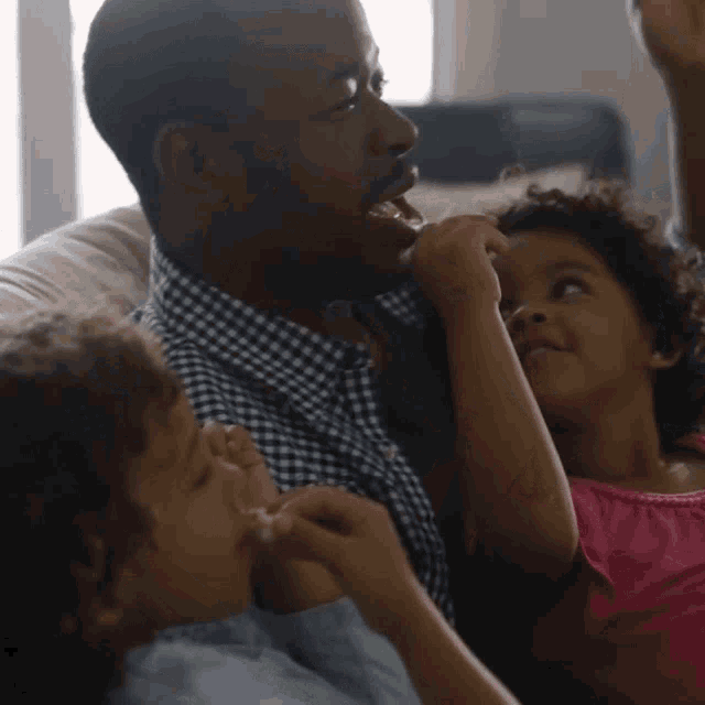 a man sits on a couch with two young children