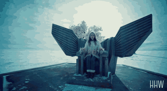 a woman sits on a statue with the word hw on the bottom right