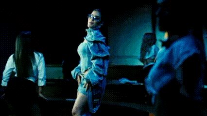 a woman is dancing in a dark room with other people .