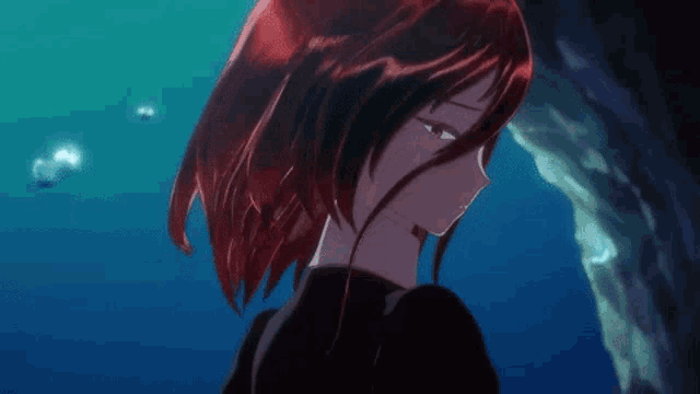 a girl with red hair is standing in a cave in the ocean .