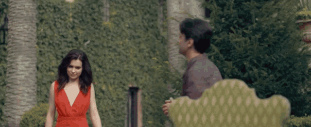 a woman in a red dress is walking next to a man in a plaid shirt