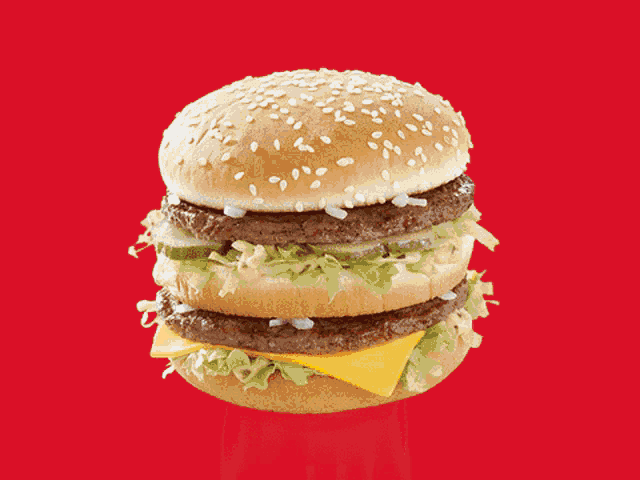 a mcdonald 's big mac sandwich with lettuce cheese and pickles on a red background