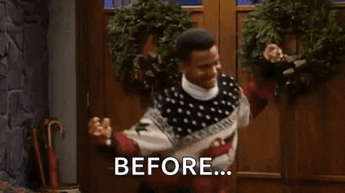 a man in a christmas sweater is standing in front of a door with a wreath on it .